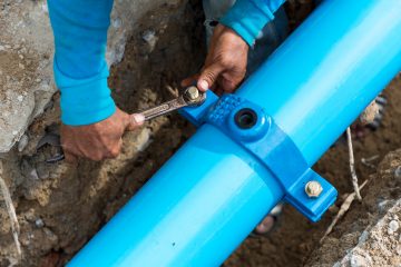 Man using a large wrench on water pipes. Construction site with